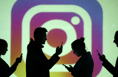 El logotipo de la red social Instagram y sombras de 4 personas utilizando su teléfono celular. 