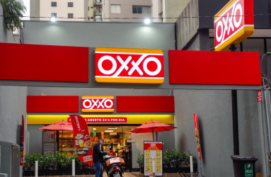 Una tienda Oxxo con una persona en moto parada afuera. 