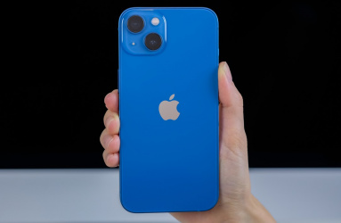 Una mano sostiene un iPhone 13 ebn color azul. 
