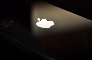 Logotipo de Apple sobre un iPhone color negro colocado entre luz y sombra. 