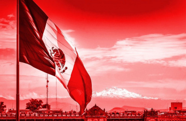 Bandera de México en el Zócalo, de fondo se observa el Palacio Nacional y un volcán, en un tono color rojo. 