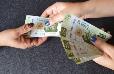 manos de mujeres pagando y recibiendo billetes mexicanos de 200 pesos