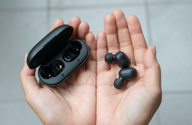 Mano mostrando audífonos inalámbricos de color negro 