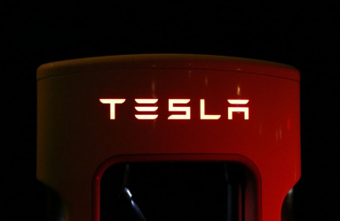 Logo rojo de Tesla en medio de la oscuridad. 