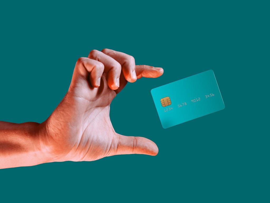Una mano intentando agarrar una tarjeta bancaria. 