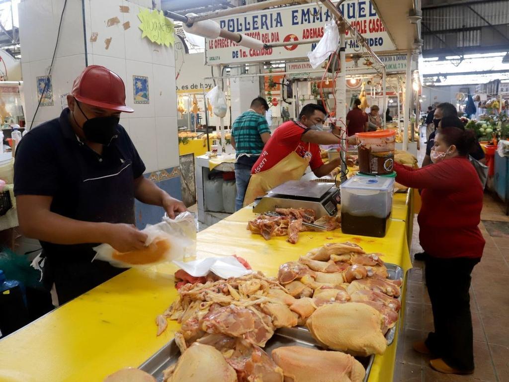 Vendedores del alimento pollo en mercado y una clienta recibiendo su cambio de dinero. 