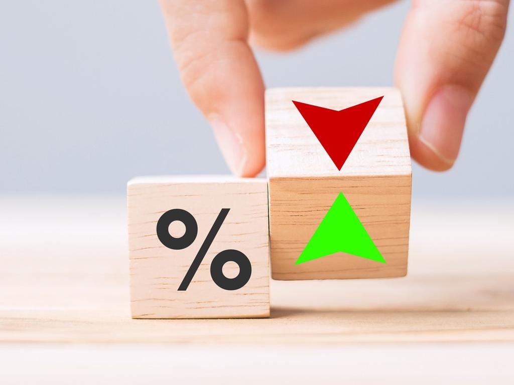 Un dado con el símbolo de porcentaje y unos dedos sostienen otro con una flecha verde y otra roja. 