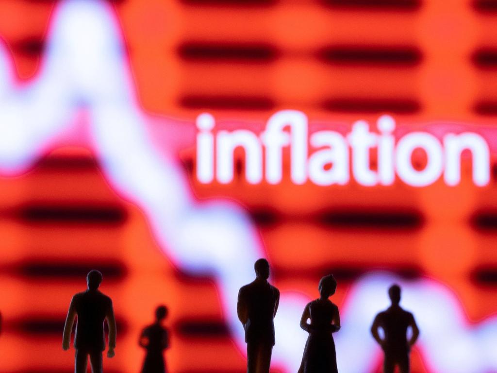 Las sombras de 5 personas y al fondo una gráfica blanca sobre un fondo rojo y la palabra inflación en inglés. 