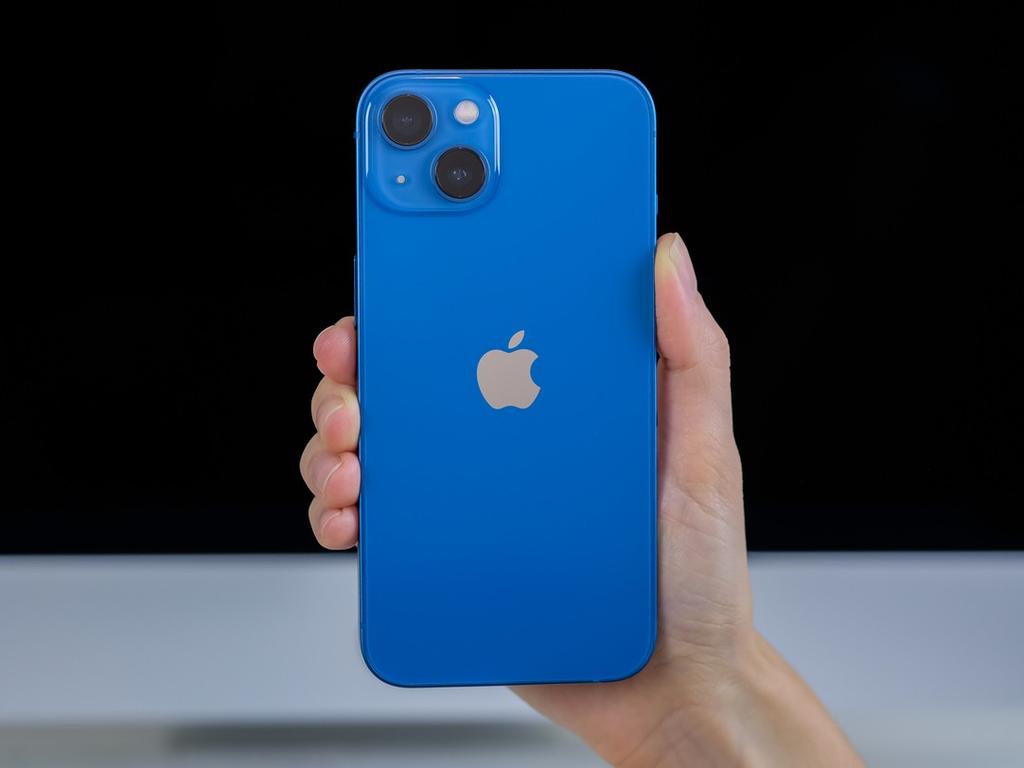 Una mano sostiene un iPhone 13 ebn color azul. 