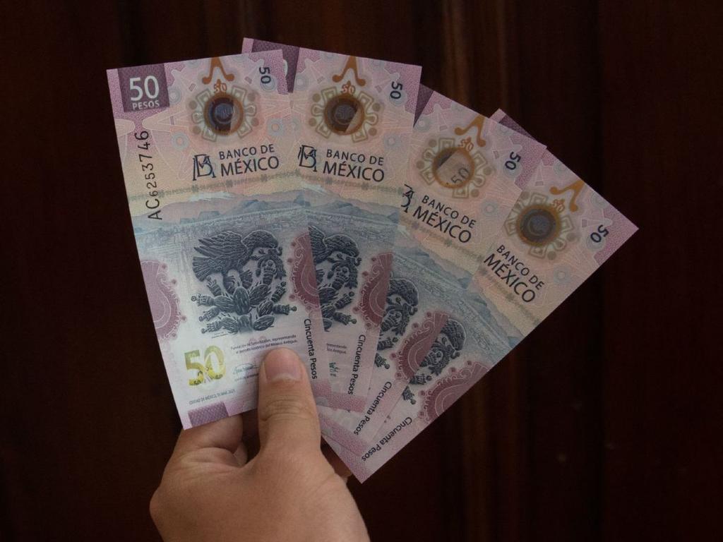 Mano sosteniendo extendidos 3 nuevos billetes de 50 pesos