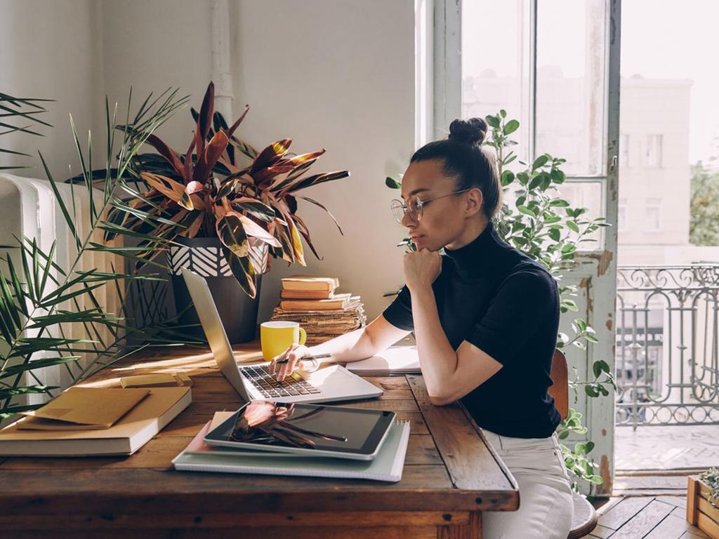 mujer sentada trabajando en casa frente a escritorio