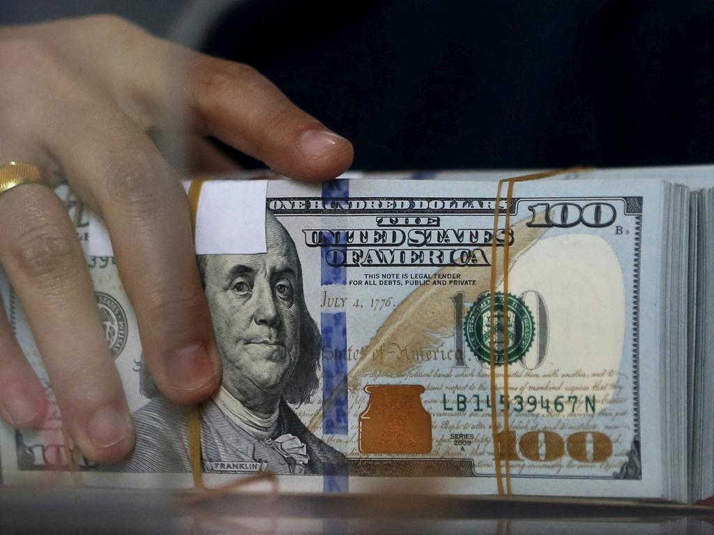 Una manos sostiene un fajo de billetes dólar. 