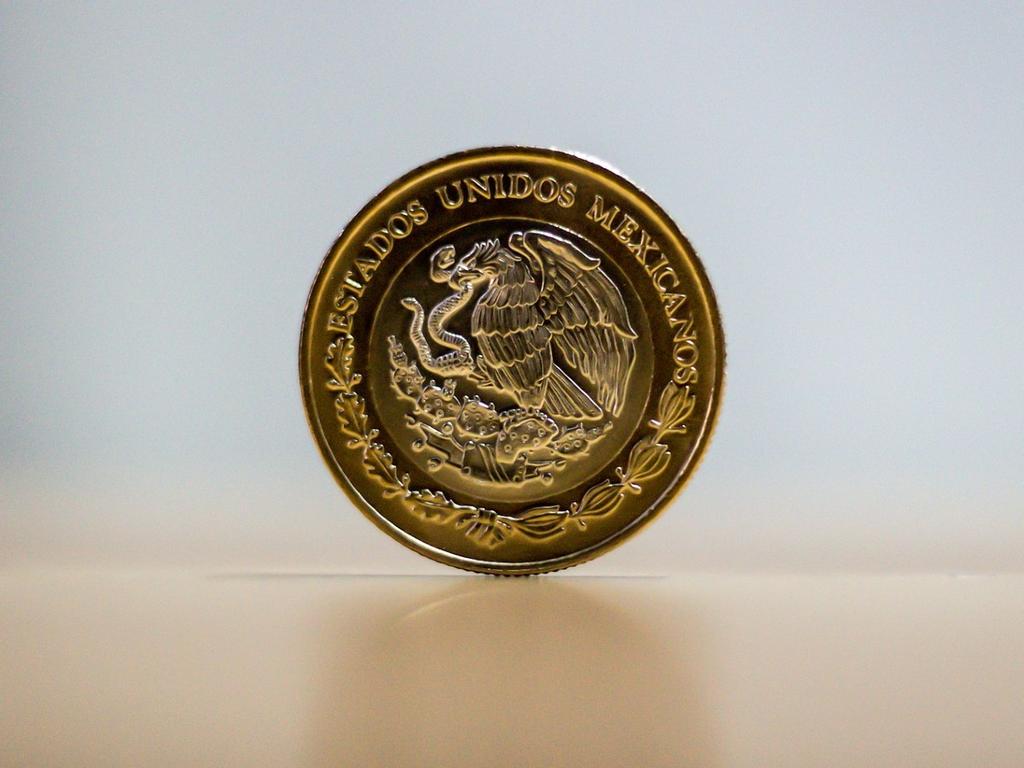 Una moneda de diez pesos en color dorado y con el escudo de México. 