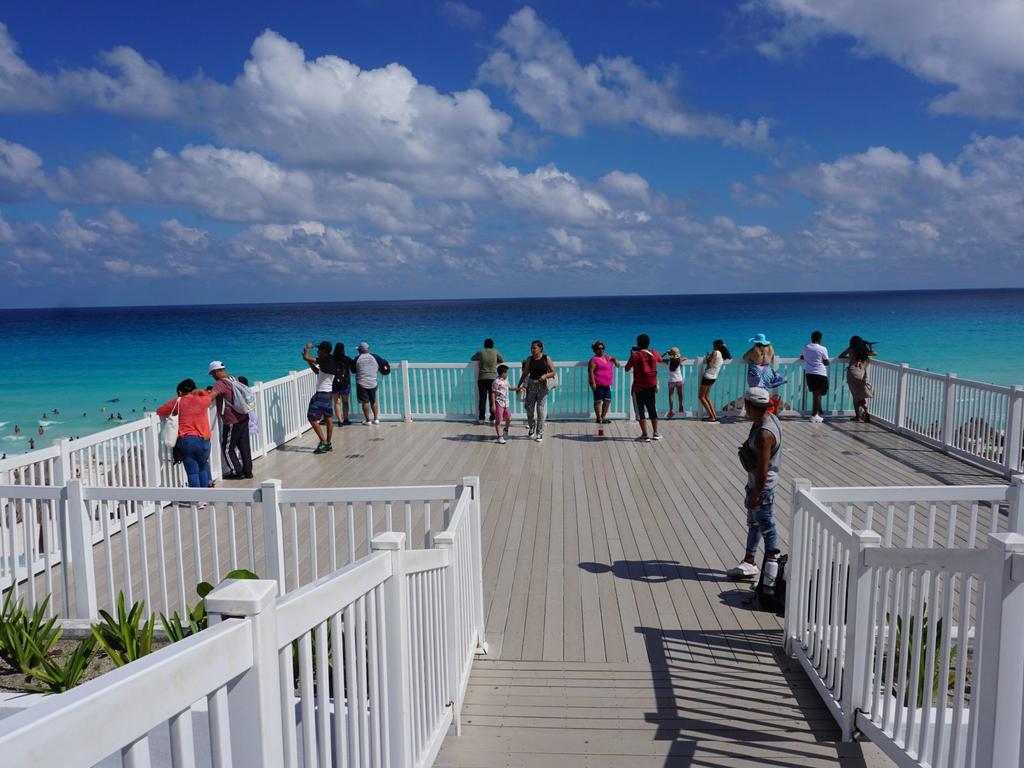 Varias personas observando el mar desde un balcón de madera. 