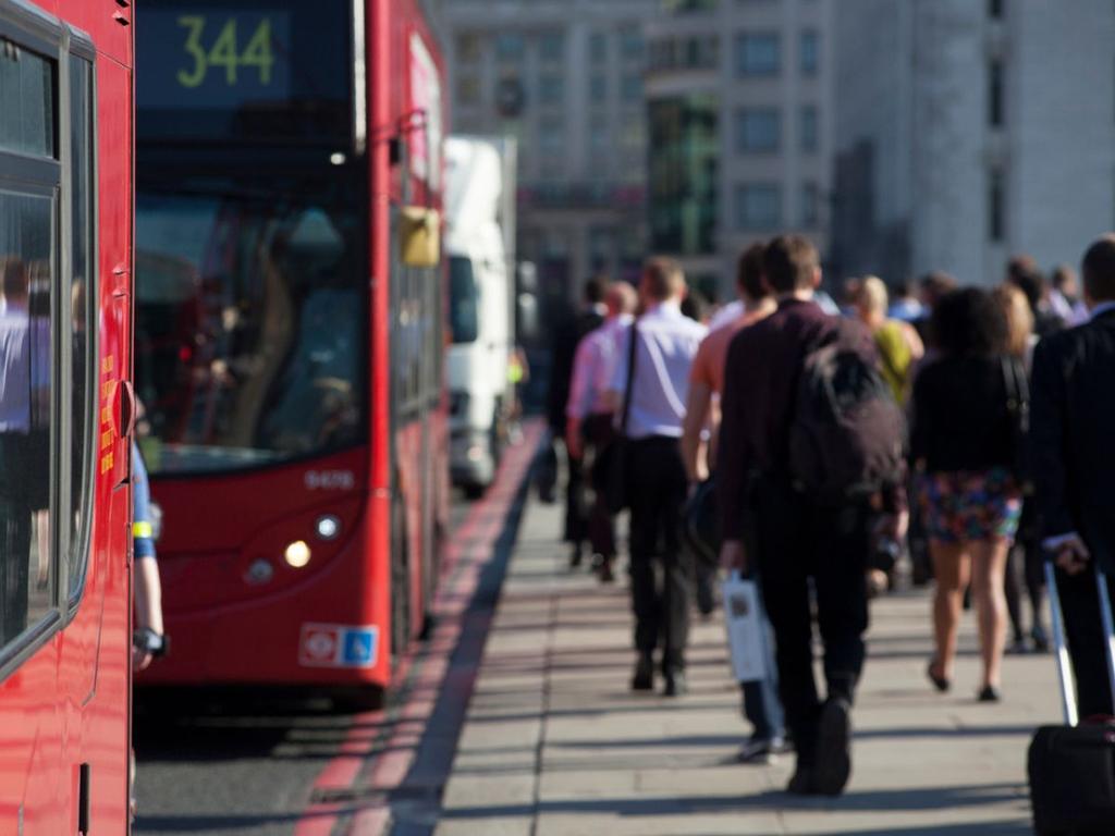 Autobuses rojos de Londres y varios trabajadores caminando. 