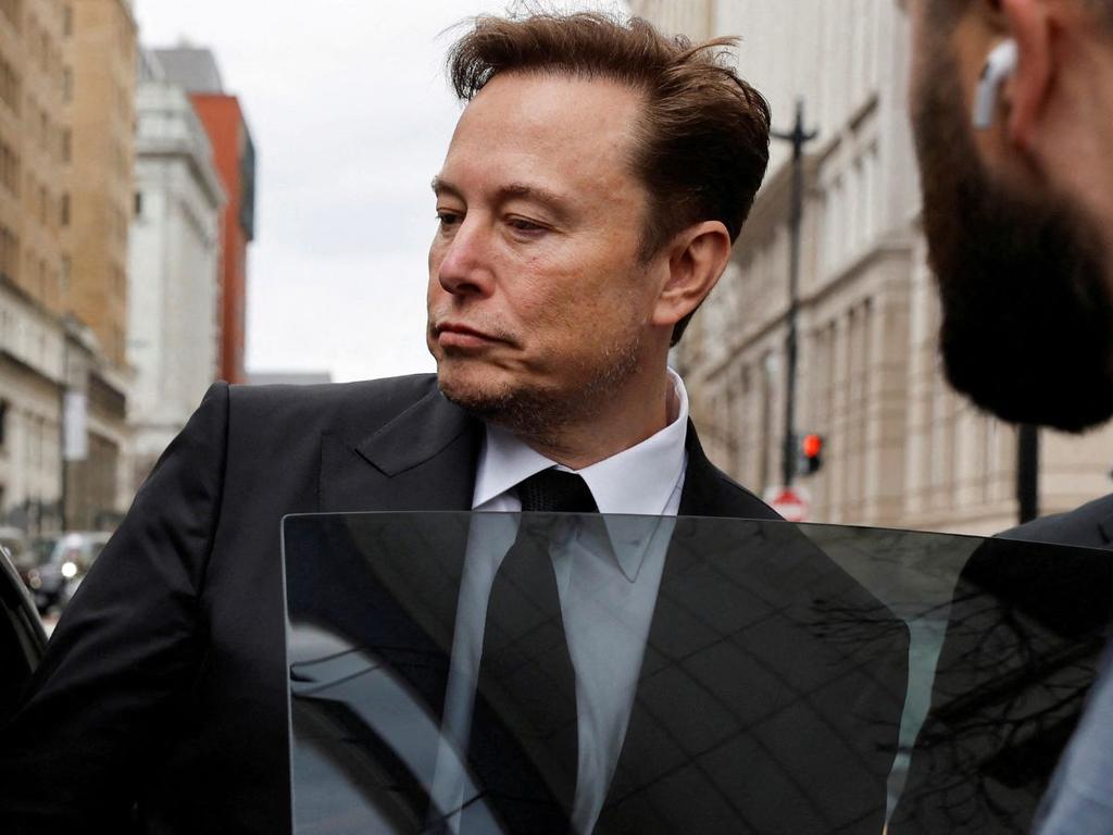Elon Musk de pie vestido de traje negro