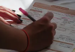 Una mano escribe datos en una solicitud de empleo. 