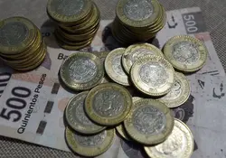 Billete de 500 pesos abajo de varias monedas de 10 pesos
