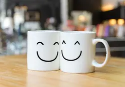 Dos tazas blancas con cara de felicidad