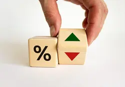 Una mano mueve un dado con flecha verde y roja, otro dado con un símbolo de porcentaje. 