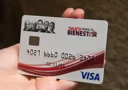 Una mano sostiene una tarjeta bancaria color blanco del Banco del Bienestar y VISA. 