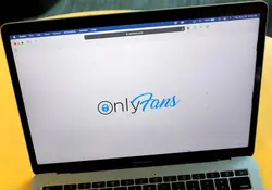 Una laptop con la pantalla blanca y el ícono de OnlyFans con una superficie color amarilla. 