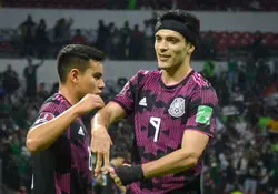Dos jugadores de la selección de futbol de México en la cancha con el uniforme. 