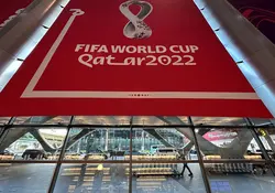 Un letrero del evento deportivo Qatar 2022 en color rojo blanco colocado sobre los cristales de un edificio.
