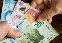 Manos sostienen billetes mexicanos de diferente valor 