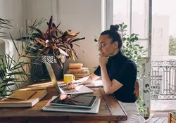mujer sentada trabajando en casa frente a escritorio