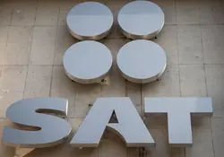 Logotipo del Servicio de Administración Tributaria (SAT) en color plateado y colocado sobre una pared. 