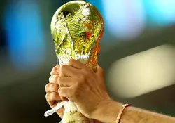 Unas manos sostiene una imitación del trofeo de la Copa del Mundo. 