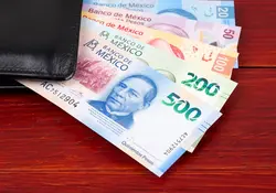 Dinero mexicano sobresale de una cartera color negro 