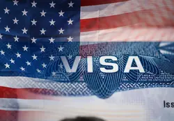 Primer plano de la visa americana con la bandera de Estados Unidos de fondo