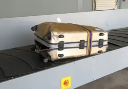 Una maleta completamente rota en una banda de un aeropuerto