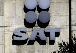Logotipo del SAT en color plateado y sobre una pared. 
