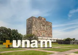 Edificio de la UNAM con letras blancas colocadas sobre el jardín. 