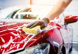 Trabajador lavando el coche rojo con esponja 