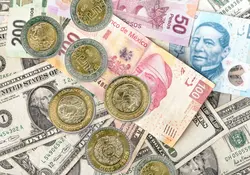 Monedas y billetes mexicanos sobre montón de dólares 