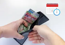 Hombre abriendo su cartera con billetes mexicanos 