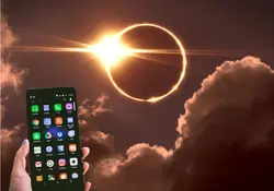 Eclipse solar y mano sosteniendo un celular encendido 