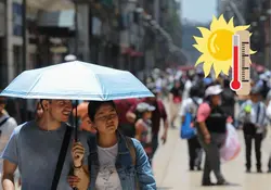 Pareja usa un paraguas para cubrirse del sol 