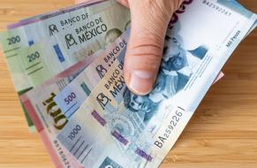 Manos sostienen billetes mexicanos 