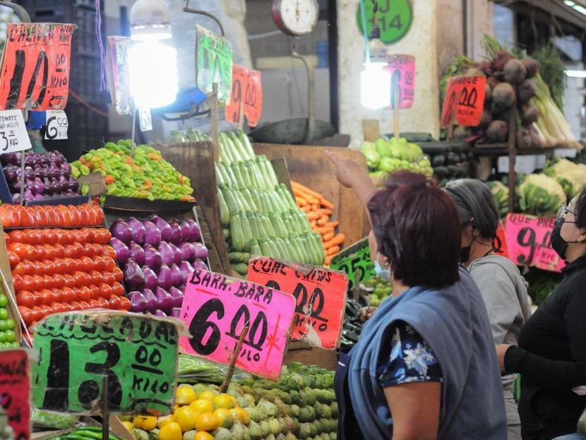 Señoras mexicanas compran verduras en un puesto de mercado. 