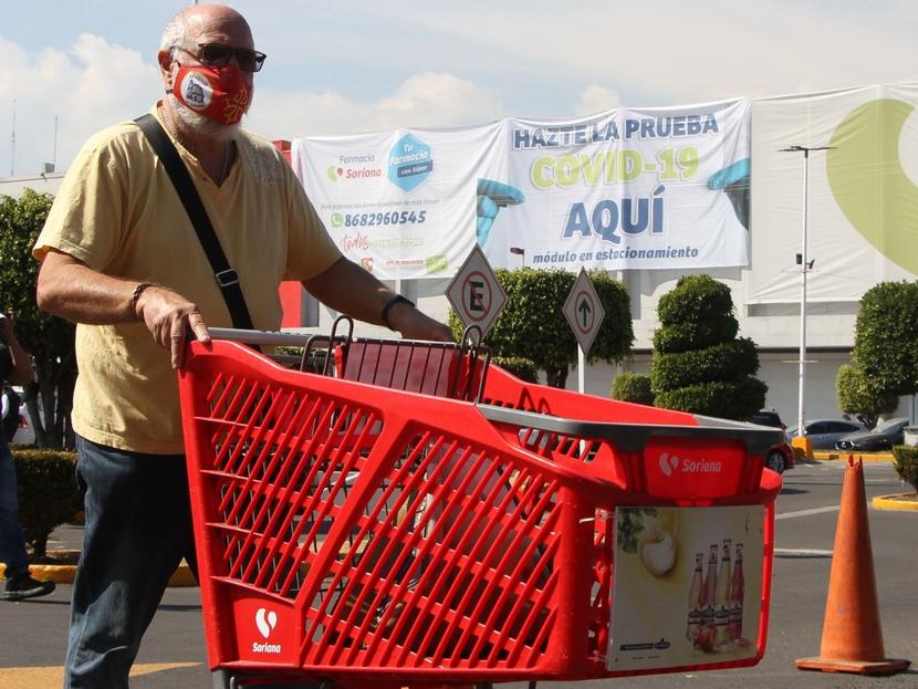 Un hombre con un carrito de supermercado color rojo. 