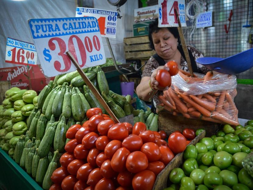 Una vendedora atiende su puesto de verduras en un mercado popular de México.  