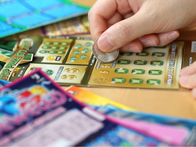 Mujer raspa billete de lotería con una moneda 