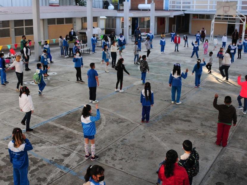 Un patio de escuela con muchos niños jugando. 