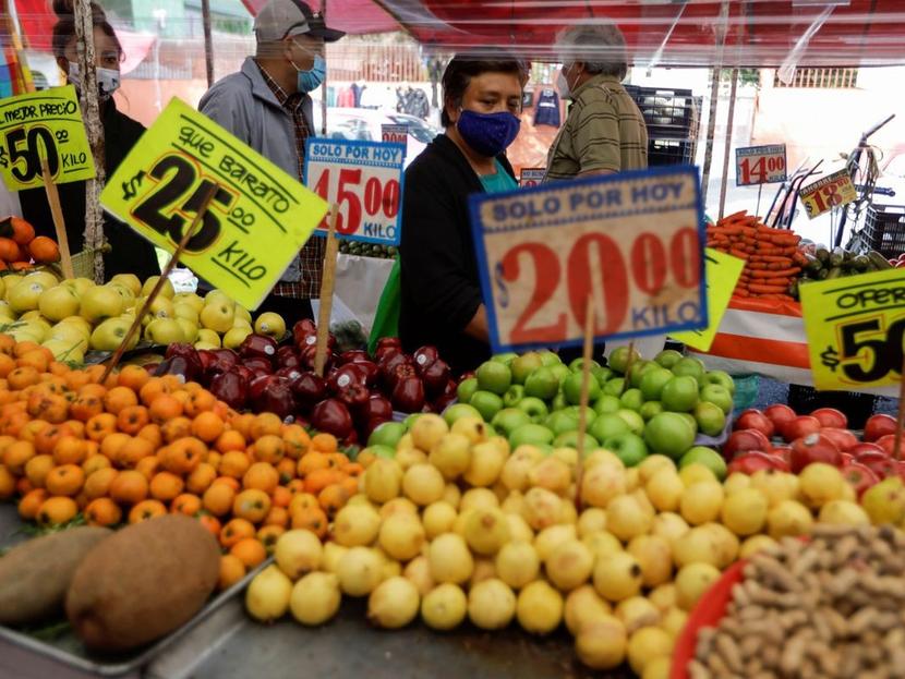 Venta de fruta en un mercado popular con personas caminado a un costado. 