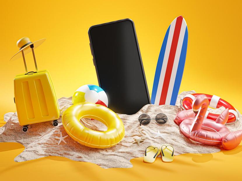 Maleta y celular junto a objetos de playa en fondo amarillo 